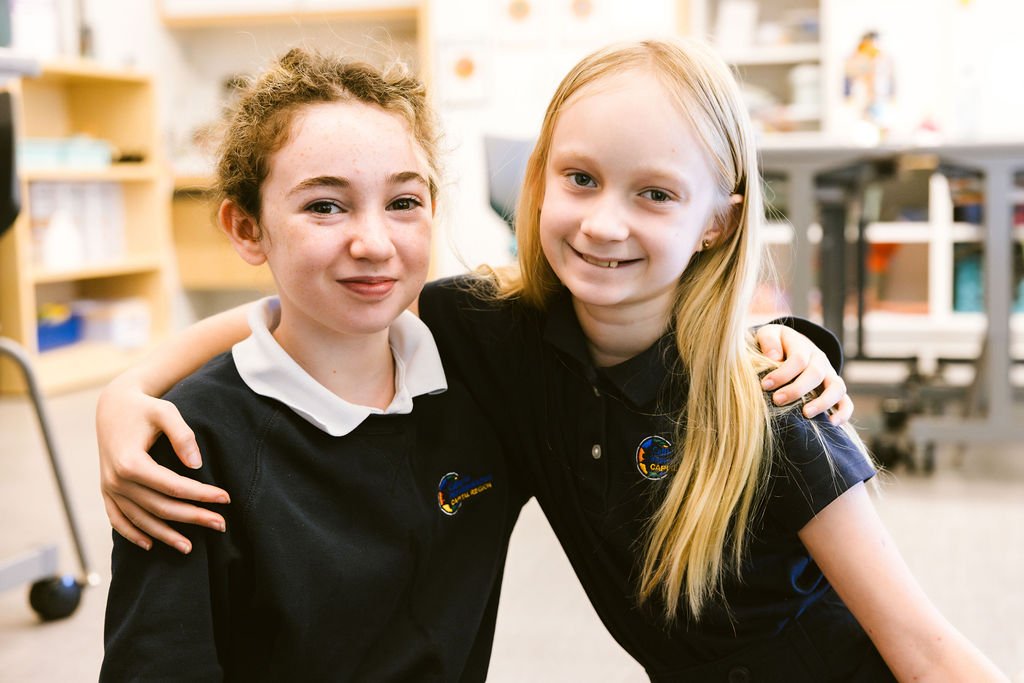 Two students with arms around each other's shoulders.
