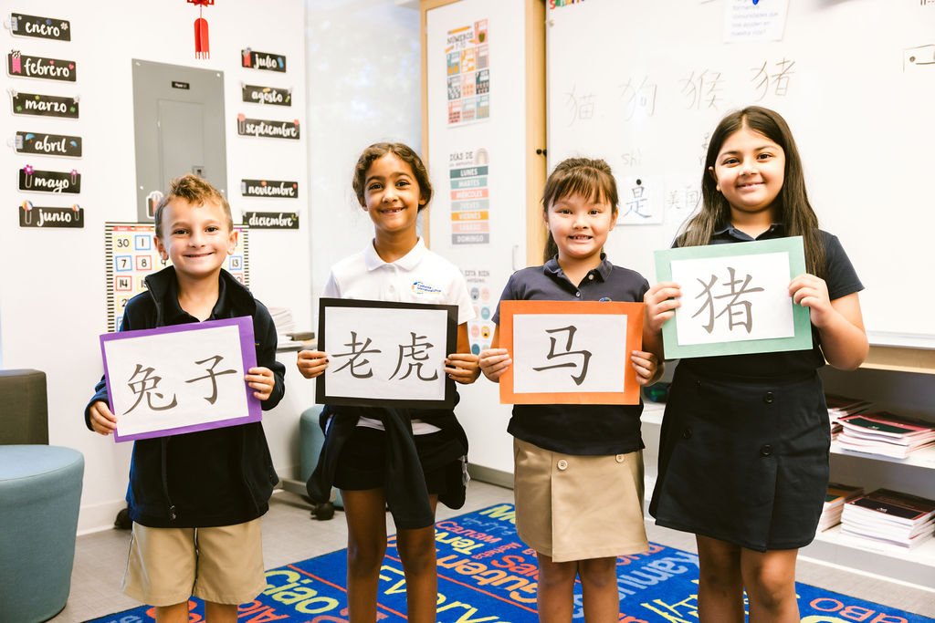 Four kids holding up posters of Chinese characters.