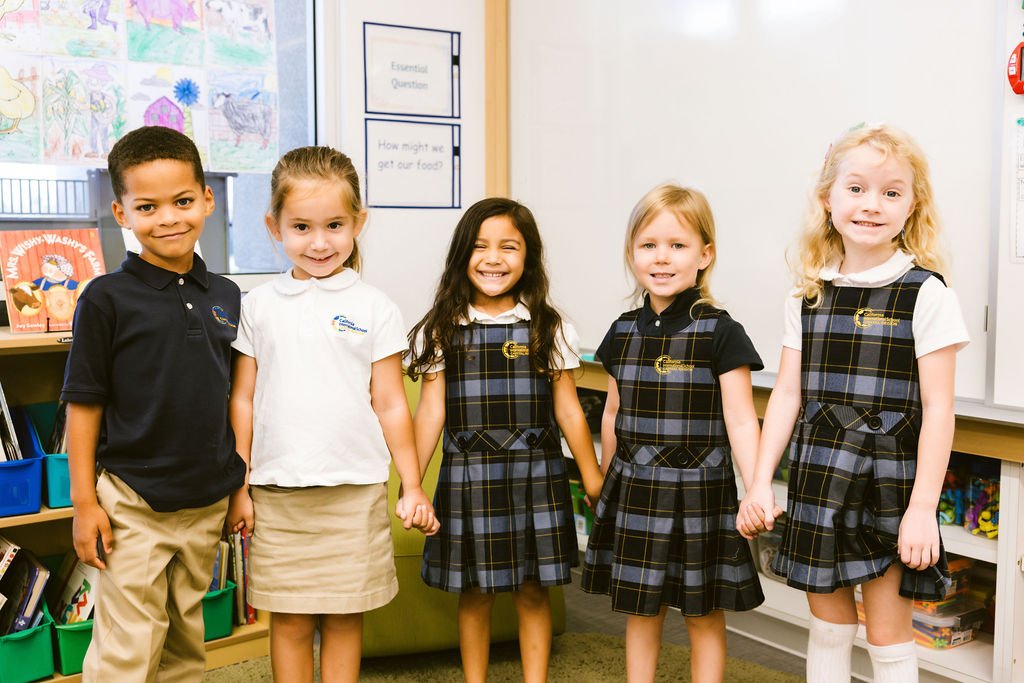 Four elementary students in school uniforms holding hands