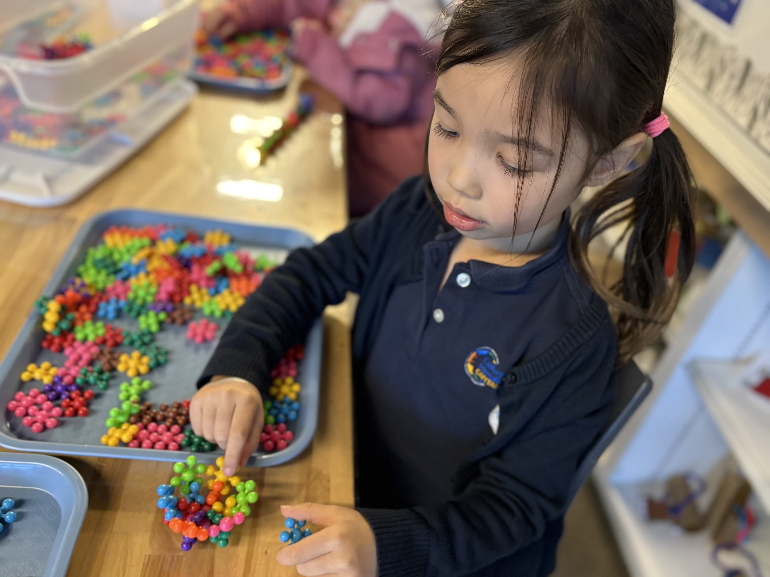 Young girl engaged in hands-on learning activity, representing the innovative education awaiting new CIS applicants
