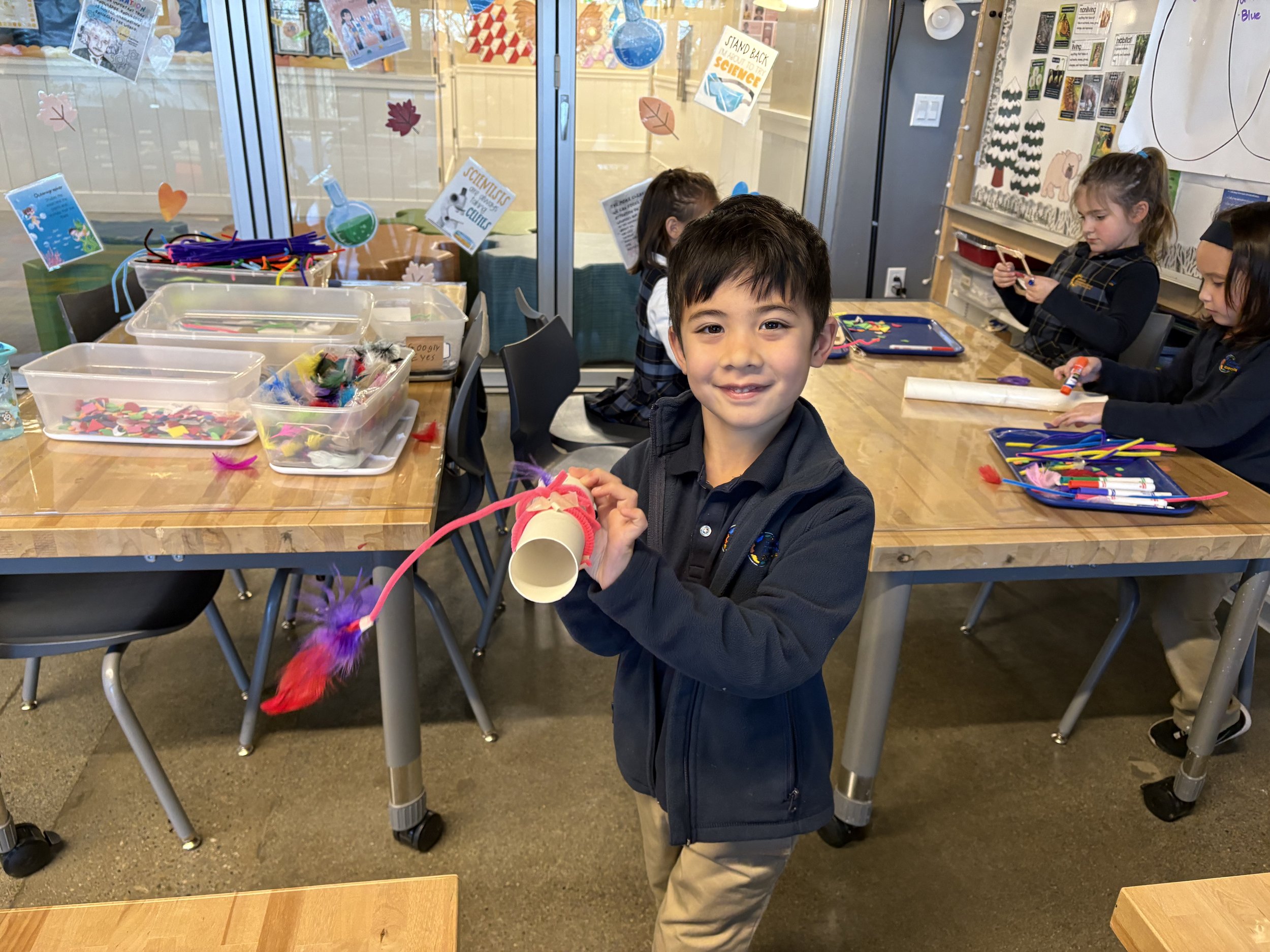 Smiling boy proudly holding up his colorful artwork, embodying CIS's vision of empowering each child with knowledge